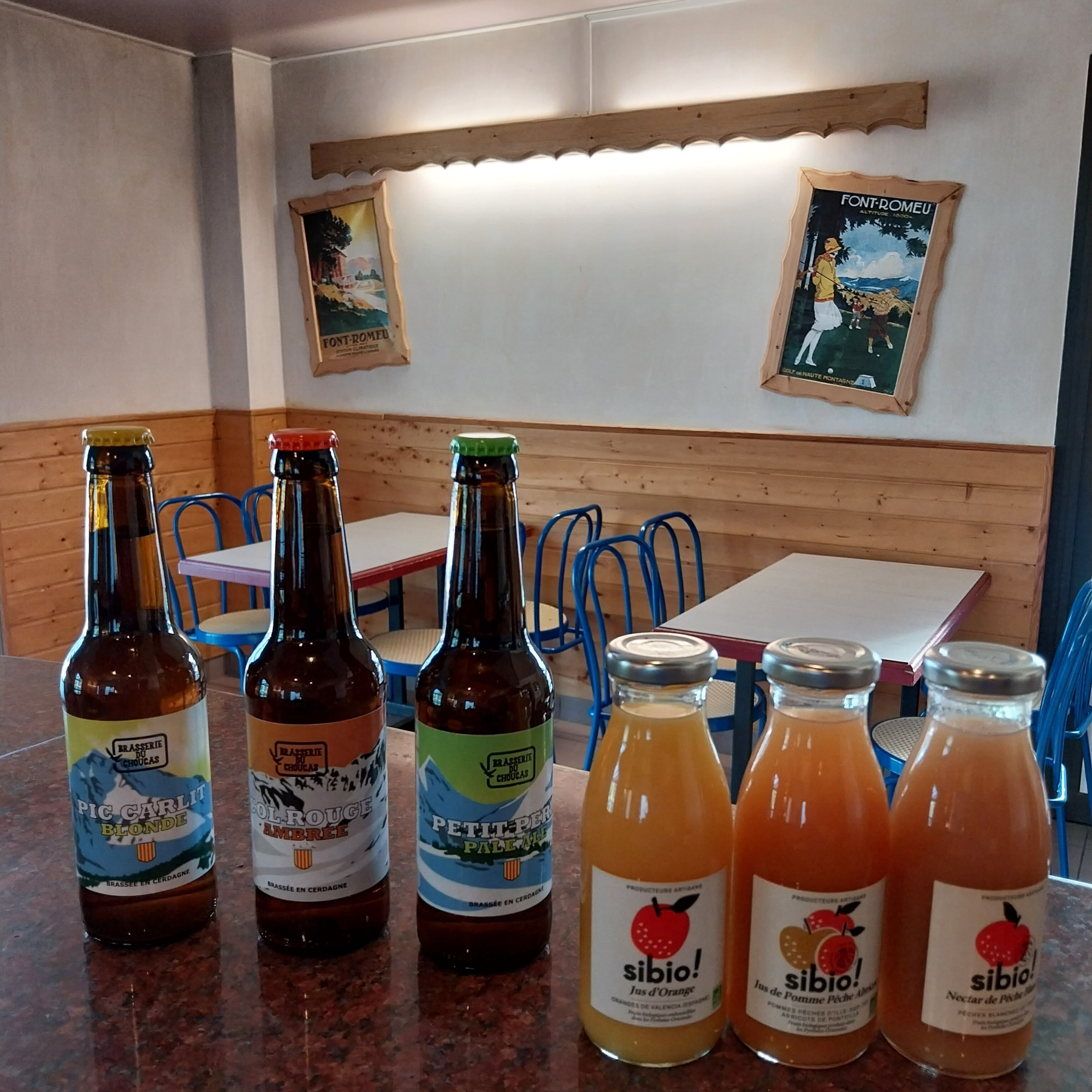 A restaurant interior with wooden paneling, tables, chairs, and various bottles of beverages on the counter.