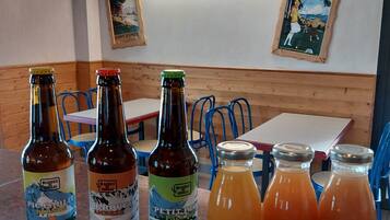 A restaurant interior with wooden paneling, tables, chairs, and various bottles of beverages on the counter.