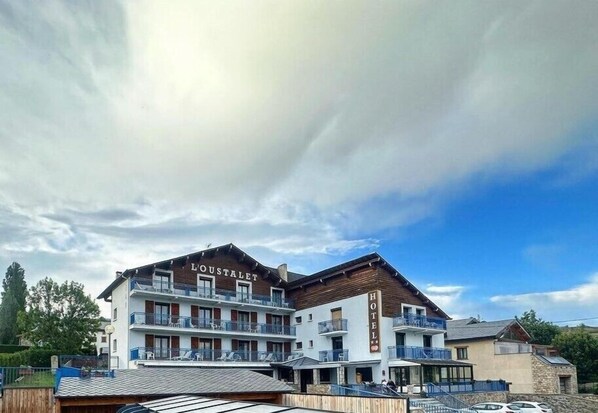 A hotel with multiple balconies, a wooden facade, and a clear sky.