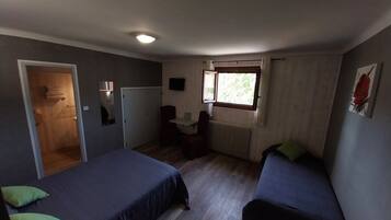 Una stanza con due letti, una scrivania, un termosifone, una finestra e una porta.
