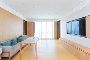 Una sala de estar moderna con un sofá, una mesa de centro y un televisor de pantalla plana montado en la pared.