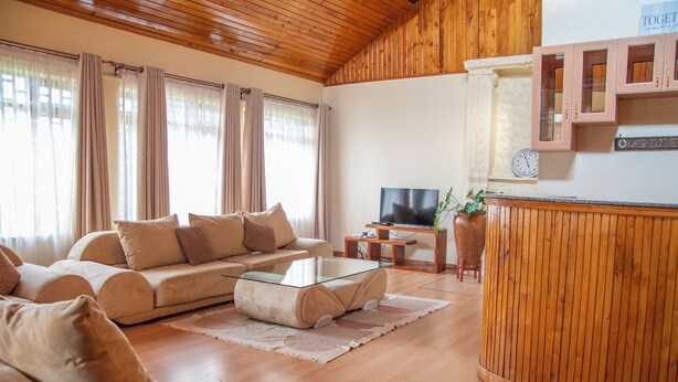 Ein Wohnzimmer mit einer Couch, einem Glastisch, einem Fernseher und Holzschränken.