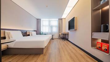 A hotel room with a large bed, a desk, a chair, a television, and a minibar.