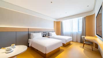 A modern hotel room with two beds, a desk, and a TV.
