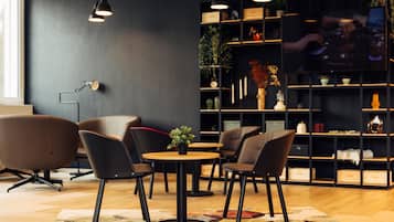 Un intérieur moderne avec une table ronde, quatre chaises, une bibliothèque et un téléviseur.