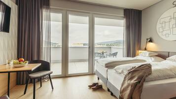 Une chambre d’hôtel comprenant un lit, un bureau avec une chaise, une table à manger avec des chaises, et une vue sur la ville par la fenêtre.