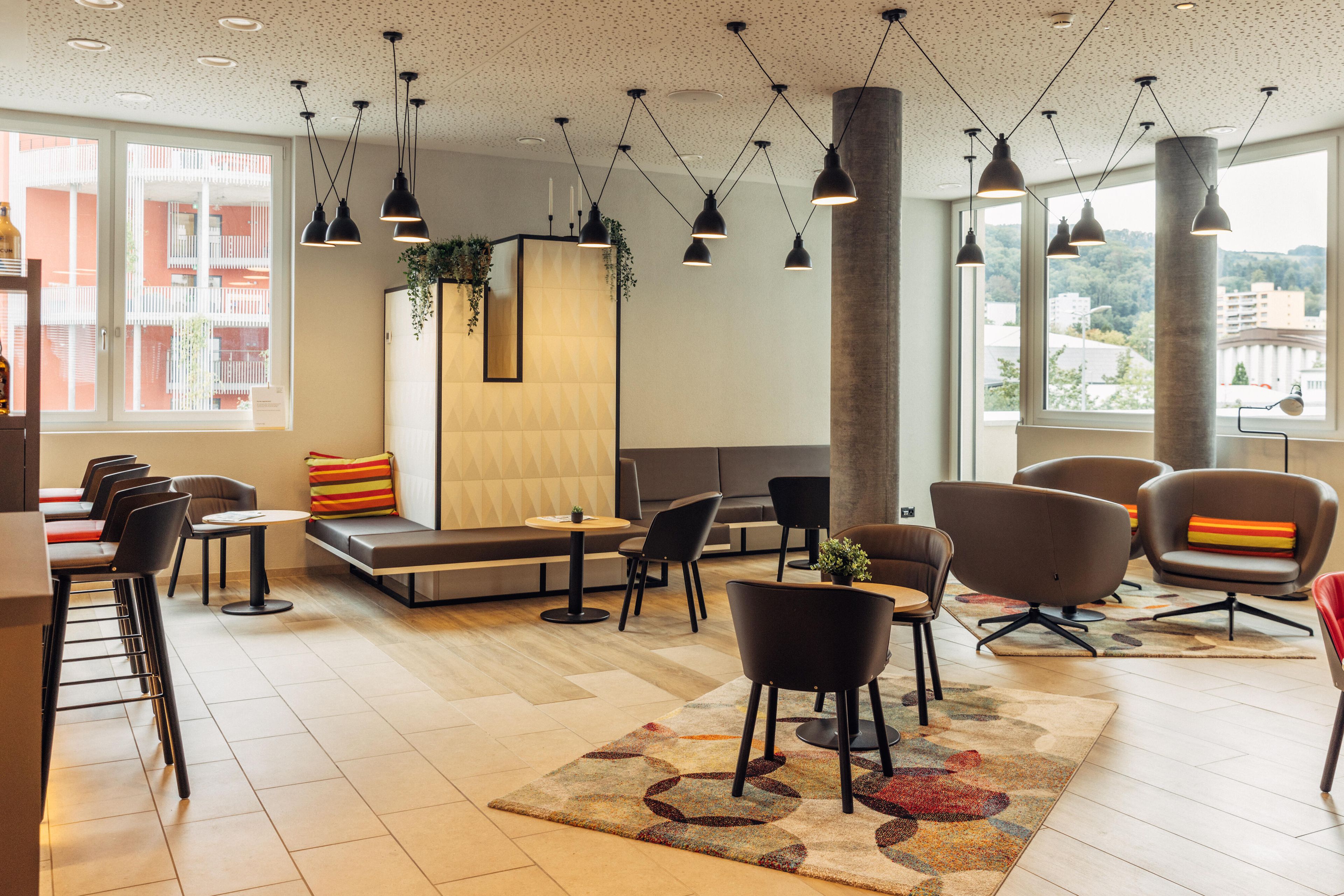Un vestíbul d'hotel modern amb zona de seients, bar i grans finestres que ofereixen vistes a la ciutat.