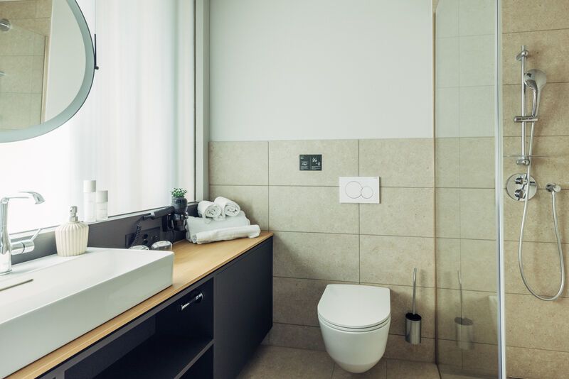 Ein modernes Badezimmer mit Waschbecken, Spiegel, Toilette und Dusche.