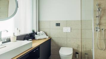 Ein modernes Badezimmer mit Waschbecken, Spiegel, Toilette und Dusche.