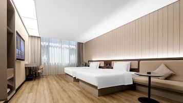 Una habitación de hotel moderna con una cama grande, un sofá, una mesita y un televisor.