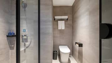 Un baño moderno con cabina de ducha de vidrio, inodoro y toallero.