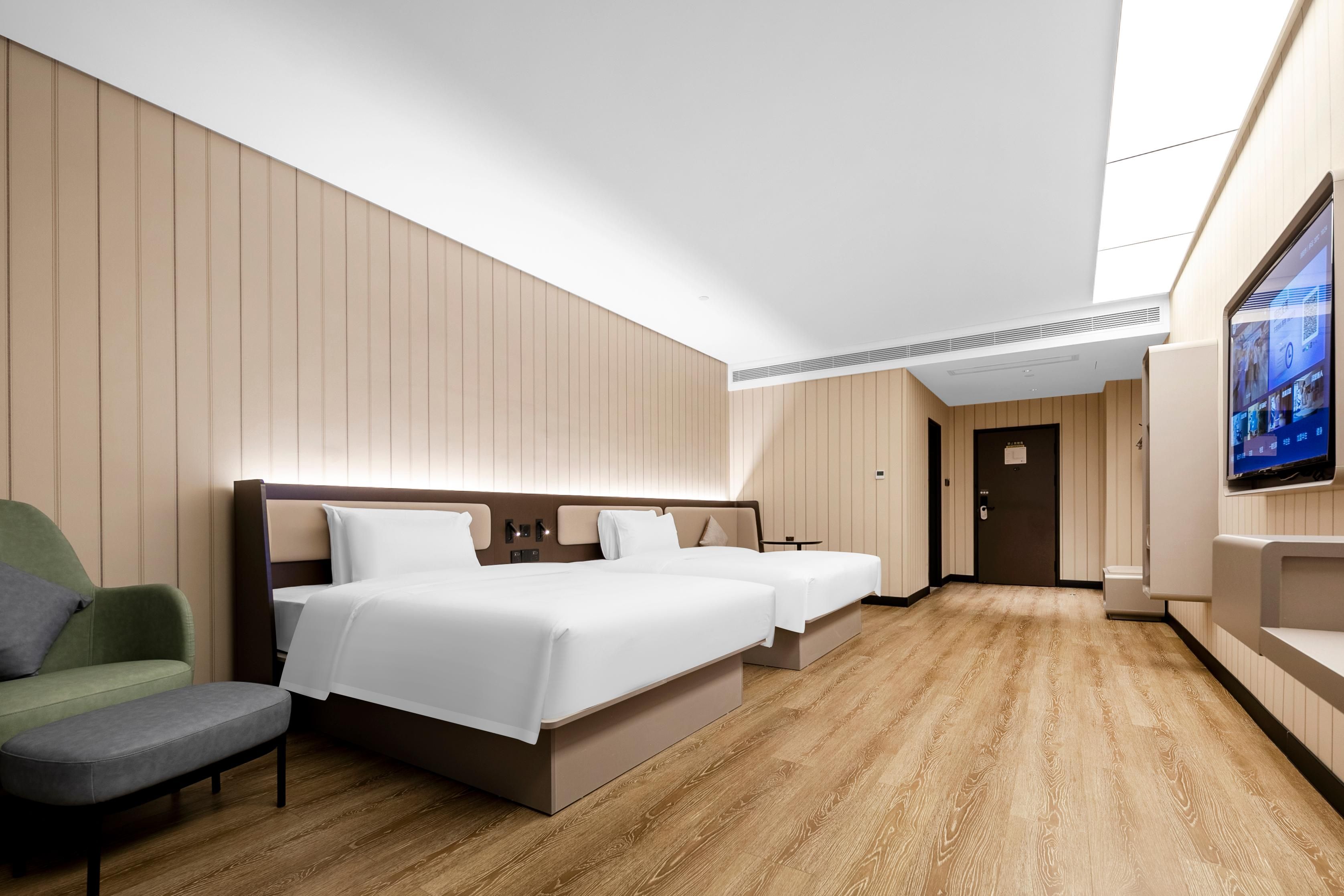 A hotel room with a large bed, a smaller bed, a seating area, and a television on the wall.