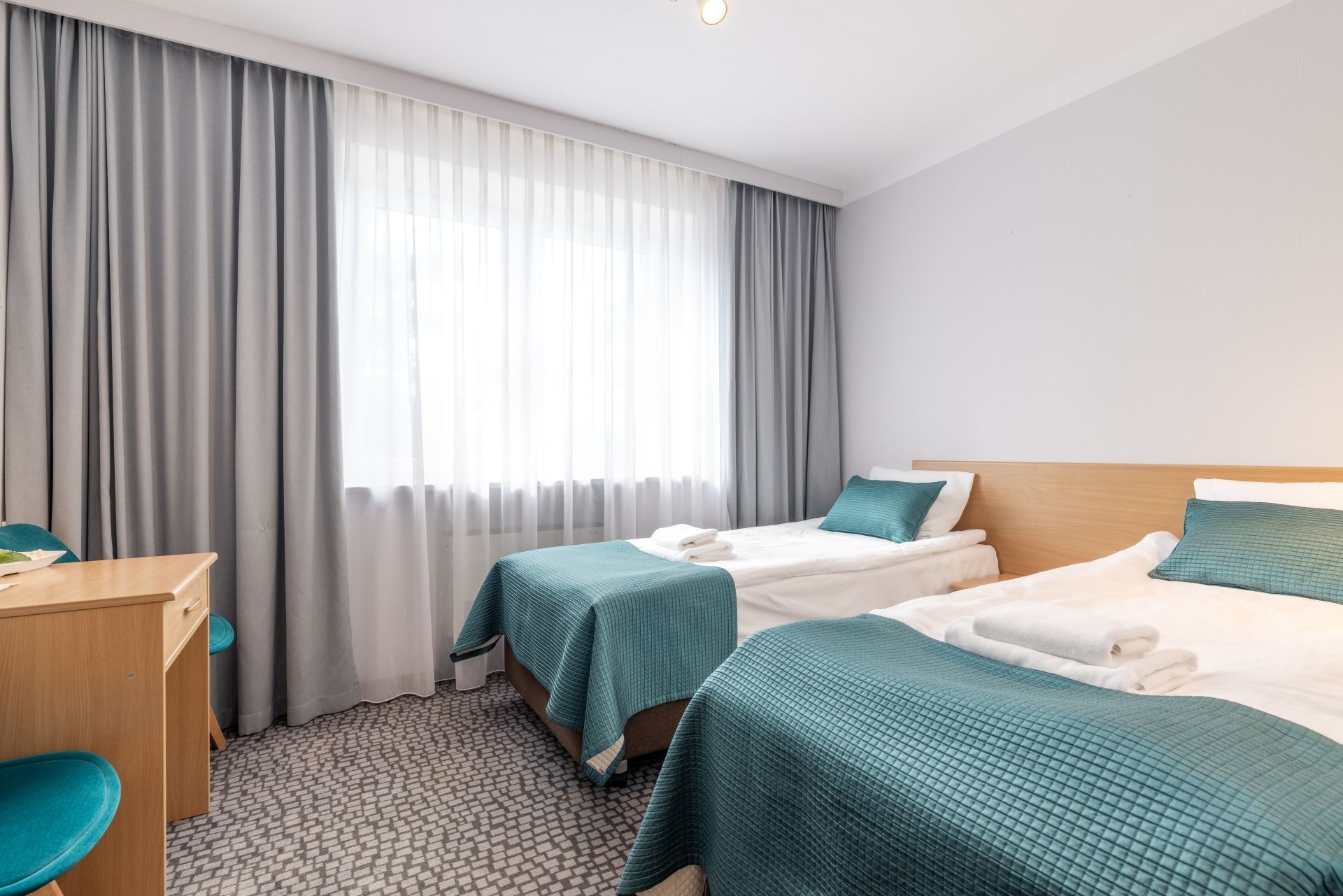 A hotel room with two beds, a desk, and a chair.
