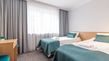 A hotel room with two beds, a desk, and a chair.