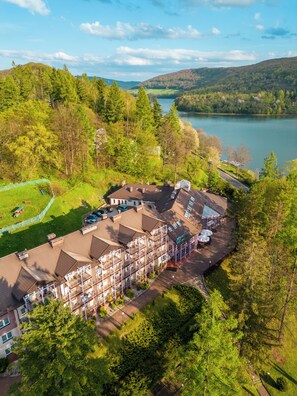 A multi-story hotel with a rooftop terrace, surrounded by lush greenery and a lake. - Hotel Solina Resort & Spa (Solina)