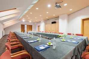 A conference room with a long table, red chairs, and a projector on the ceiling. - Hotel Solina Resort & Spa (Solina)
