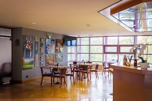 A dining area with wooden tables and chairs, a TV mounted on the wall, and artwork on the walls. - Hotel Solina Resort & Spa (Solina)