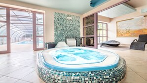 A modern indoor pool area with a mosaic-tiled hot tub, large windows, and a view of the outdoors. - Hotel Solina Resort & Spa (Solina)