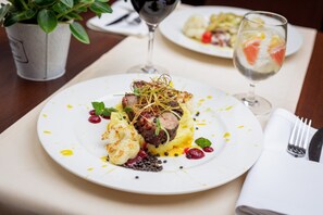 A dining table with a plate of food, a glass of red wine, and a potted plant. - Hotel Solina Resort & Spa (Solina)