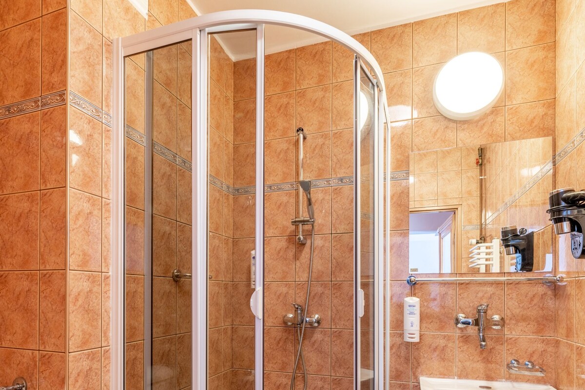 A bathroom with a glass-enclosed shower, a sink, and a toilet.