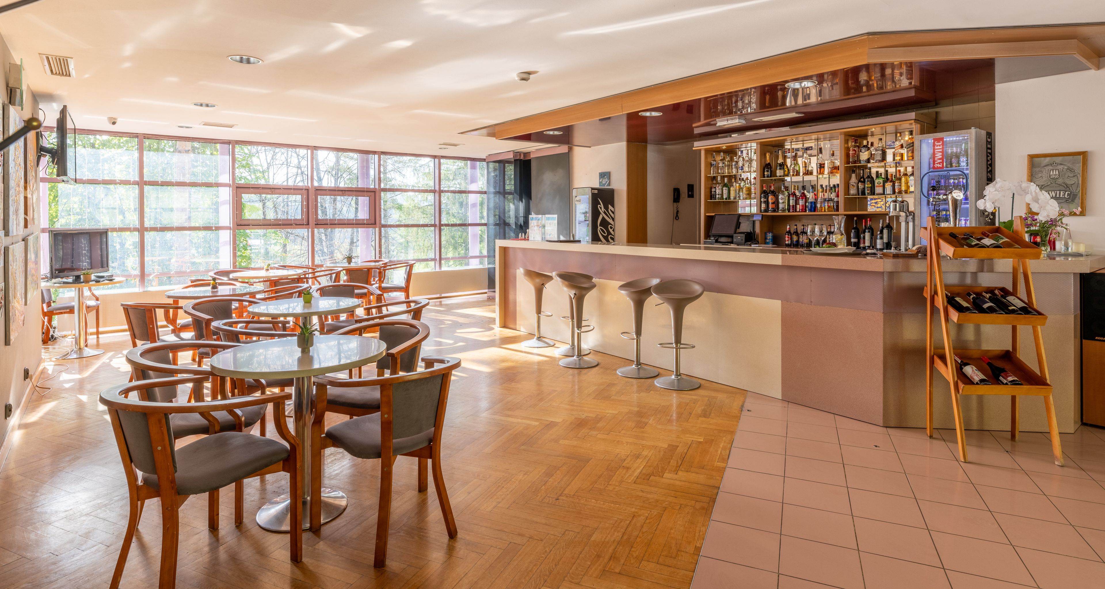 Un amplio bar con una barra de madera, varios taburetes y una gran variedad de botellas y copas.
