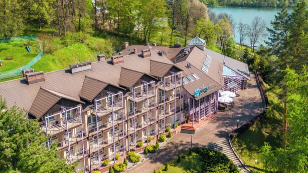A multi-story hotel with a rooftop terrace, surrounded by lush greenery and a lake view. - Hotel Solina Resort & Spa (Solina)