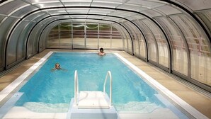 Una piscina interior con techo de cristal y una persona nadando.