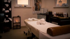 Un cuarto de spa con una camilla de masaje, toallas, un estante con botellas y un cartel en la pared.