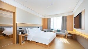 Una camera d'albergo moderna con un letto grande, una scrivania, un divano e una televisione.