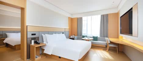 Una habitación de hotel moderna con una cama grande, un escritorio, un sofá y un televisor.