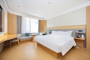 Una habitación de hotel moderna con una cama grande, un escritorio, una silla, una mesita pequeña y un sofá.