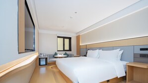 Una moderna camera d'albergo con un ampio letto, comodini, una piccola scrivania e una finestra.
