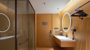 A modern bathroom with a glass shower enclosure, a wooden vanity with a mirror, and a towel rack.