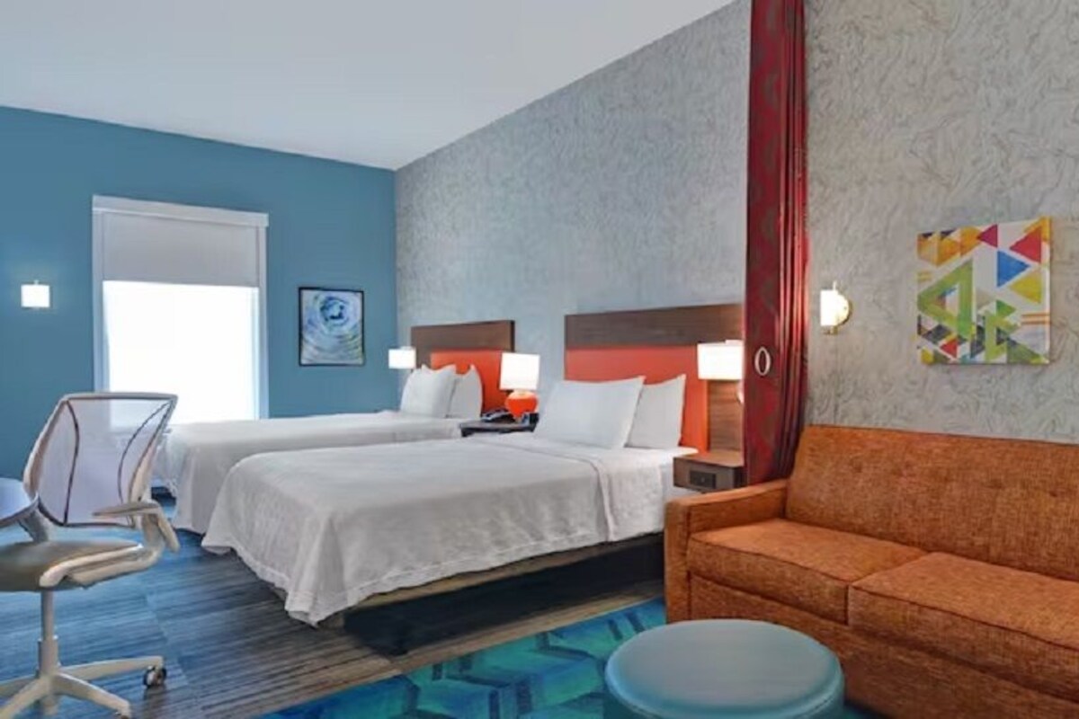 Une chambre d’hôtel avec deux lits, un canapé, un bureau et une chaise.