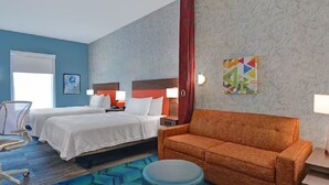 Une chambre d’hôtel avec deux lits, un canapé, un bureau et une chaise.