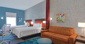 Ein Hotelzimmer mit zwei Betten, einer Couch, einem Schreibtisch und einem Stuhl.