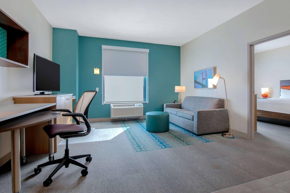 Habitació d'hotel amb escriptori, cadira, sofà i llit.