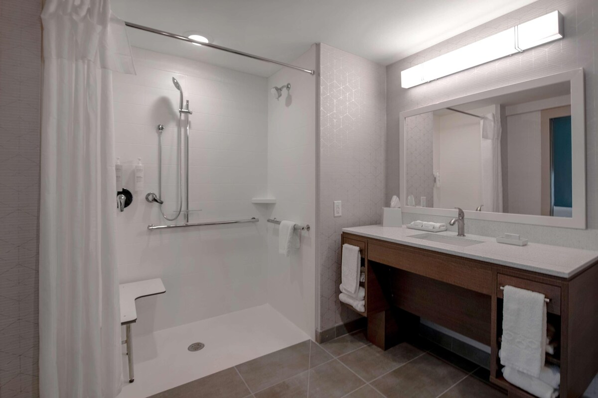 Une salle de bain moderne avec une douche à l’italienne, un meuble-lavabo avec un miroir et des toilettes.