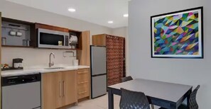 Eine moderne Küche mit integrierten Geräten, ein Essbereich mit Tisch und Stühlen sowie ein farbenfrohes abstraktes Gemälde an der Wand.