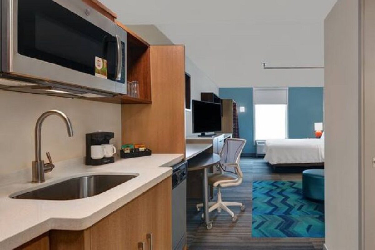 Une chambre d’hôtel équipée d’une kitchenette, d’un lit, d’un bureau et d’une salle de bain.