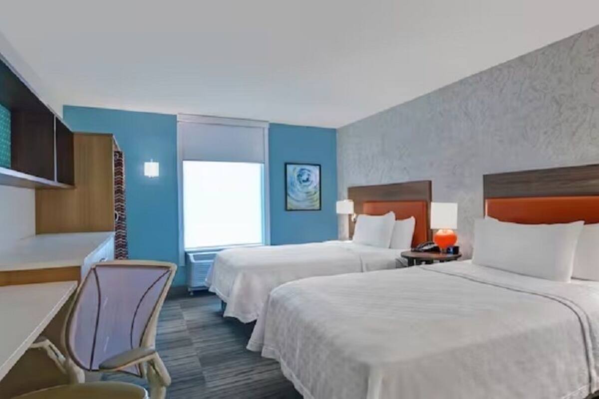 Habitació d'hotel amb dos llits, una taula de treball i una cadira.