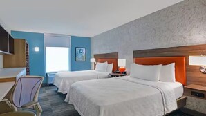 Une chambre d’hôtel avec deux lits, un bureau et une chaise.