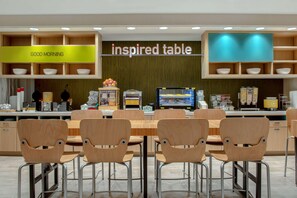 A modern cafe with a wooden table and chairs, a coffee machine, and a sign that reads "inspired table". - Home2 Suites By Hilton Savannah I95 North (Port Wentworth)