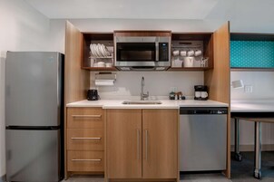 Una cocina funcional equipada con refrigerador, microondas y lavavajillas.