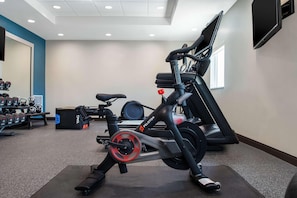 Une salle de sport équipée d’un vélo d’appartement, d’haltères et d’un banc de musculation.