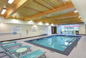 Una piscina interior amb bigues de fusta, senyals de seguretat i gandules.