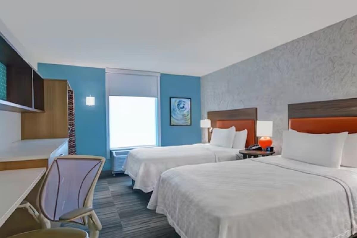 Une chambre d’hôtel avec deux lits, un bureau, une chaise et un téléviseur.