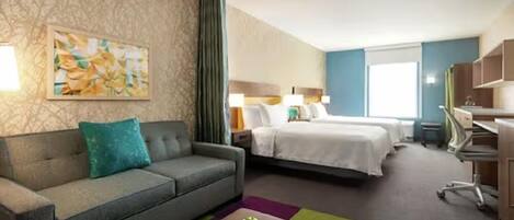 Habitación de hotel con sofá, cama, escritorio y un cuadro en la pared.