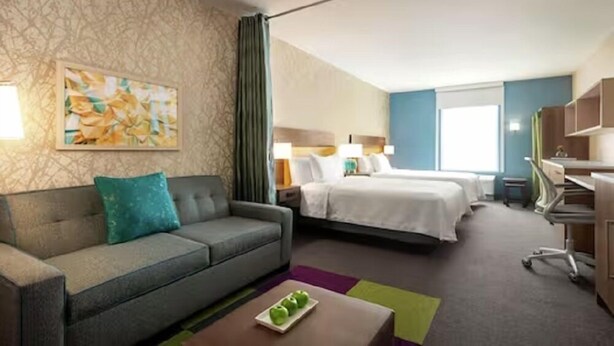 Une chambre d’hôtel avec un canapé, un lit, un bureau et un tableau au mur.