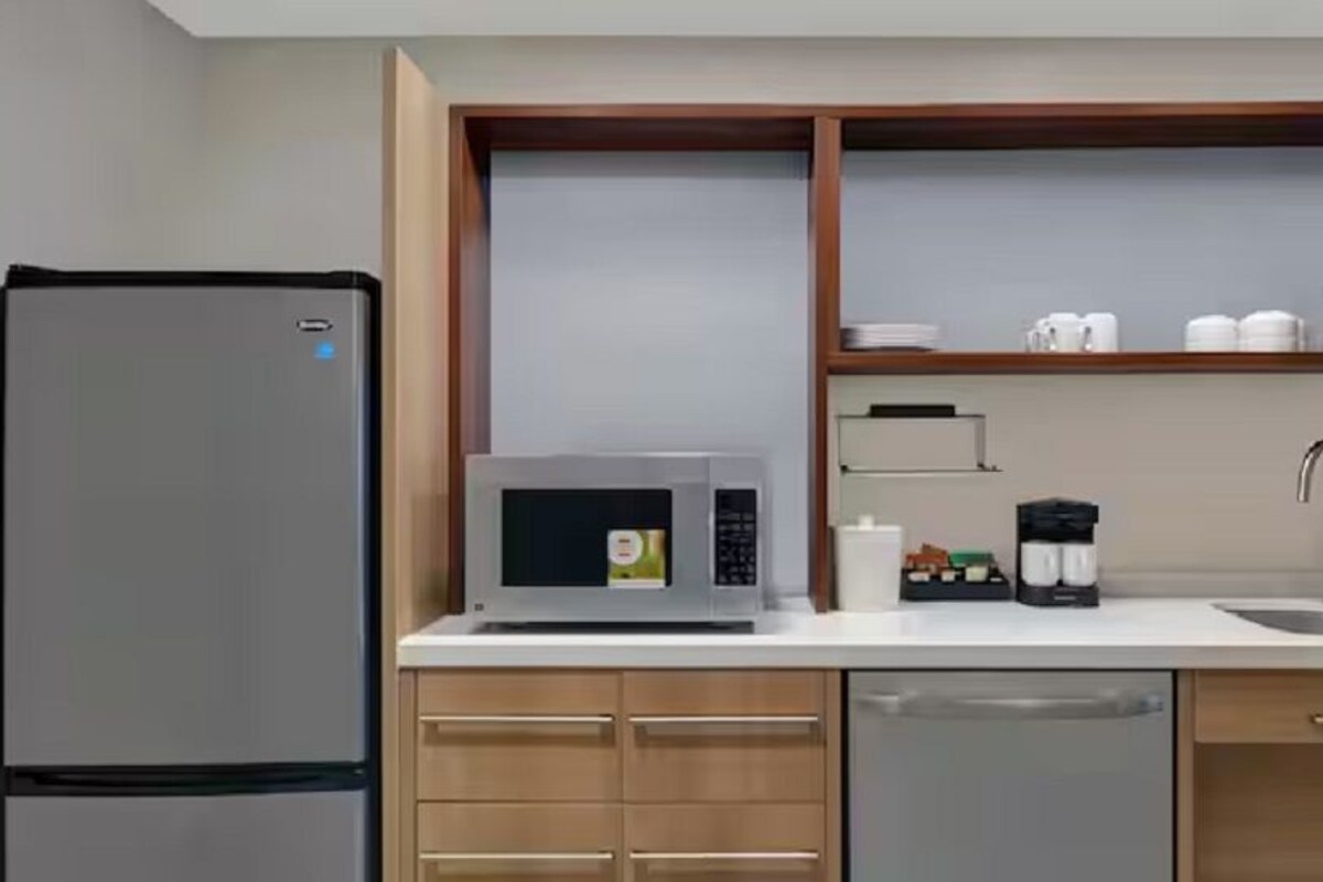 Une cuisine compacte équipée d’un réfrigérateur, d’un four à micro-ondes, d’un évier et de meubles de rangement en bois.